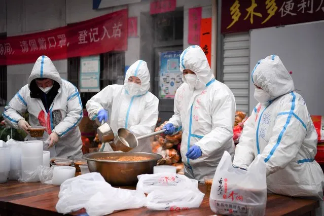 In this photo released by China's Xinhua News Agency, volunteers wearing protective suits package meals for delivery to people under lockdown in Xi'an in northwestern China's Shaanxi Province, Tuesday, January 4, 2022. Hospital officials in the northern Chinese city of Xi'an have been punished after a pregnant woman miscarried after being refused entry, reportedly for not having current COVID-19 test results. (Photo by Zhang Bowen/Xinhua via AP Photo)
