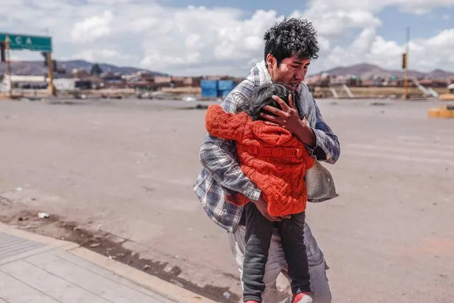 A man shields a child as he runs for cover during the protests in the vicinity of the Juliaca airport, in Juliaca, Peru, 07 January 2022. Protest demonstrations against the government of Dina Boluarte left at least 12 injured on 06 January, including 4 policemen, in clashes around the Juliaca airport in southern Peru, while the prosecutor's office began to investigate the deaths of protesters that occurred in last December. The Ombudsman's Office reported, through its Twitter account, that they went to the Carlos Monge Medrano hospital in Julicaca, and verified 'the existence of 8 civilians and 4 injured policemen', after the clashes at the Inca Manco Capac airport, which closed its operations due to the riots. (Photo by Aldair Mejia/EPA/EFE)