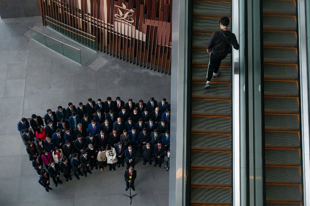 A man walks up an escalator as Hong Kong lawmakers pose for a group photo after an oath-swearing ceremony at the Legislative Council Complex on January 3, 2022 in Hong Kong, China. Hong Kong's Legislative Council is welcoming new members at a ceremony today, following a revamp of the electoral system by Beijing to ensure only “patriots” hold political power. (Photo by Anthony Kwan/Getty Images)