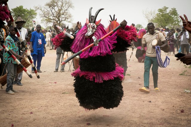 A traditional mask representing a koba (antelope) dances during the Festimasq, the Festival des Masques in Pouni, Sanguie province, on March 30, 2024. To the jerky rhythm of drums and flutes, hundreds of people parade in Pouni, a rural commune in Burkina Faso, wearing large colorful masks: in this country undermined by jihadist violence, these mystical objects of transmission must now call for peace. (Photo by Fanny Noaro-Kabre/AFP Photo)
