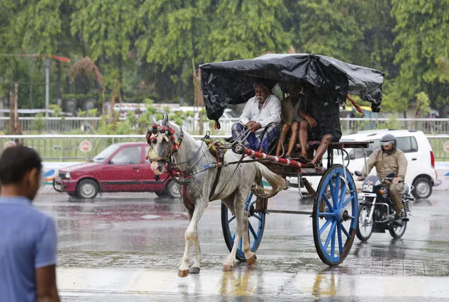 A horse cart ferries passengers in the rain in Prayagraj, in the northern Indian state of Uttar Pradesh, Wednesday, July 24, 2019. Lightning has killed more than 50 people in July, including more than 30 in Uttar Pradesh state, with thunderstorms and heavy rains lashing north and eastern India. South Asia's monsoon rains, which hit the region from June to September, are crucial for the rain-fed crops planted during the season. (Photo by Rajesh Kumar Singh/AP Photo)
