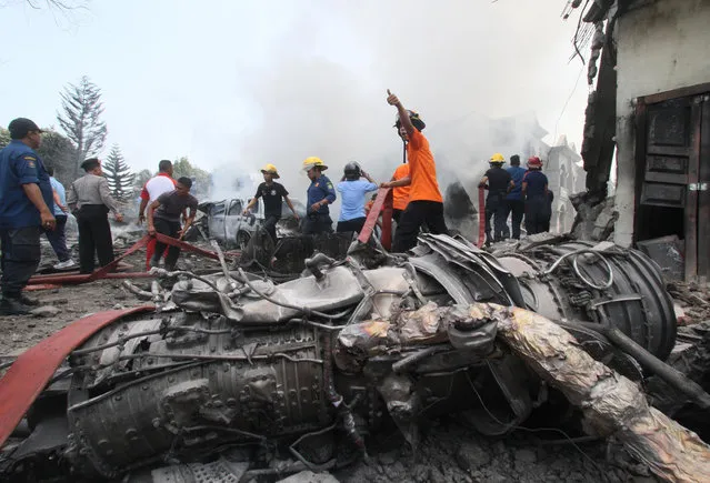 Firefighters and military personnel work at the site where an Air Force cargo plane crashed in Medan, North Sumatra, Indonesia, Tuesday, June 30, 2015. (Photo by Gilbert Manullang/AP Photo)