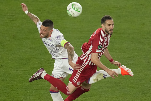 Olympiacos' Kostas Fortounis jumps for a header with Fiorentina's Cristiano Biraghi during the Conference League final soccer match between Olympiacos FC and ACF Fiorentina at OPAP Arena in Athens, Greece, Wednesday, May 29, 2024. (Photo by Petros Karadjias/AP Photo)
