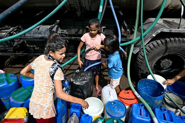 Children fill their containers with water supplied by a municipal tanker in New Delhi on June 19, 2024 amid heatwave. Searing heatwave temperatures in northern India pushed power demand to a record high, the government said on June 18, with residents of the capital New Delhi also struggling with water shortages. (Photo by Money Sharma/AFP Photo)