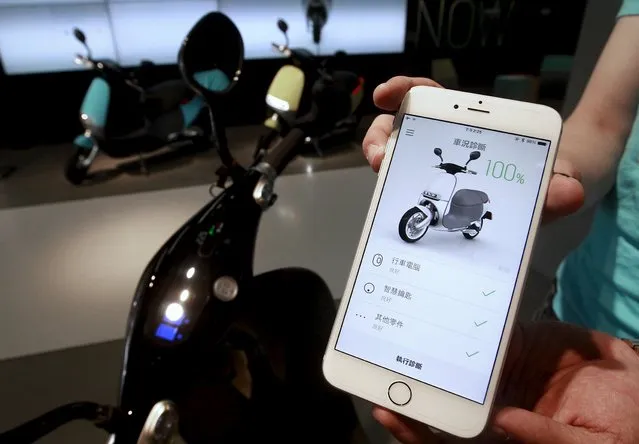 A Gogoro app is displayed on a smartphone near a Gogoro Smartscooter in its shop in Taipei, Taiwan, July 6, 2015. (Photo by Pichi Chuang/Reuters)