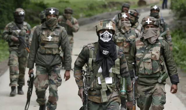 Indian army soldiers walk back towards their base camp after a search operation in Shopian, about 60 Kilometers south of Srinagar, Indian controlled Kashmir, Thursday, May 4, 2017. Thousands of Indian government forces cordoned off at least two dozen villages in southern Kashmir on Thursday while they hunted for separatist militants believed to be hiding in the area. (Photo by Mukhtar Khan/AP Photo)