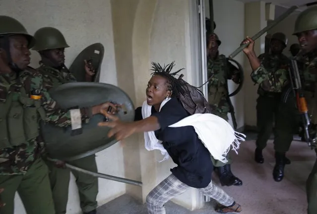 A woman flees as a riot police officer beats her with a baton, after chasing protesting students into the Nairobi University campus in Nairobi, Kenya, 20 May 2014. Hundreds of university students took to the street and faced with the riot police as they protested  against proposed increase in school fee in downtown Nairobi on 20 May. Police fired teargas and chased rioting students into the campus where they arrested students and employees found inside. (Photo by Dai Kurokawa/EPA)
