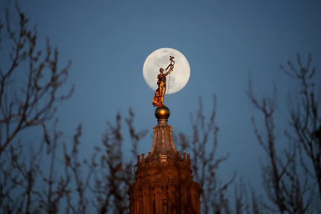 The moon rises behind a statue, known as Miss Penn or the Spirit of the Commonwealth, standing on the dome of the Pennsylvania State Capitol, Wednesday, April 20, 2016, in Harrisburg, Pa. (Photo by Julio Cortez/AP Photo)