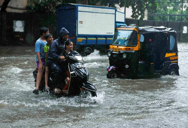 A man drives a scooter through a waterlogged street in Mumbai, India on July 21, 2024. (Photo by Francis Mascarenhas/Reuters)