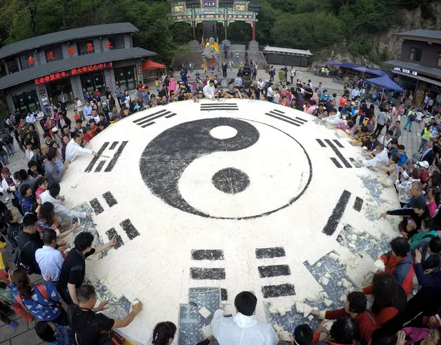 Tourists share a giant block of tofu in the shape of a Tai Chi diagram in Luoyang city, Henan province, China on May 14, 2017. (Photo by Imaginechina/Rex Features/Shutterstock)