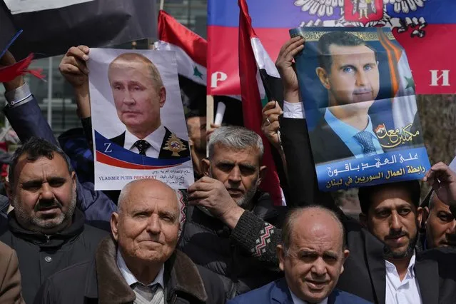 People hold portraits of Russian President Vladimir Putin, left, and Syrian President Bashar Assad, right, during a demonstration in support of Russia's invasion of Ukraine, in front of the U.N. headquarters in Beirut, Lebanon, Sunday, March 20, 2022. Dozens of Lebanese, Syrians and Russians gathered to support Putin whose military joined Syria's civil war in 2015 helping tip the balance of power in favor of President Bashar Assad's forces. (Photo by Bilal Hussein/AP Photo)