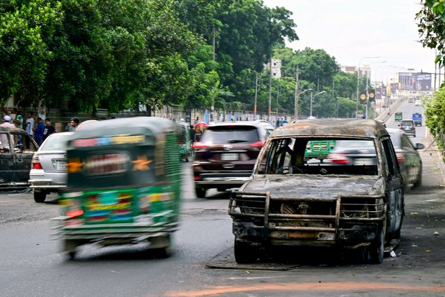 Commuters drive past a burnt car after students set it on fire amid the ongoing anti-quota protest in Dhaka on July 19, 2024. Bangladesh woke on July 19 to survey destruction left by the deadliest day of ongoing student protests so far, which saw government buildings torched by demonstrators and a nationwide internet blackout put into effect. (Photo by Munir Uz Zaman/AFP Photo)