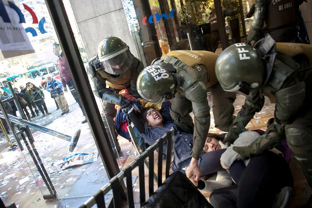 A demonstrators is detained by riot police during a protest inside the headquarters of the Chilean Chamber of Construction, demanding housing solutions for their neighbourhoods in Santiago, Chile May 19, 2017. (Photo by Cristobal Saavedra/Reuters)