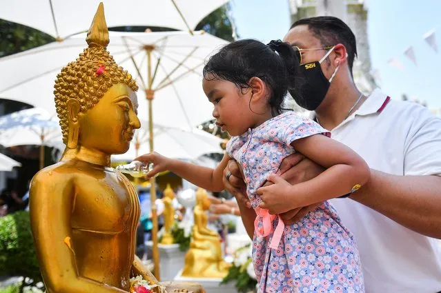 A girl pours water on a Buddha statue during the Songkran holiday which marks the Thai New Year, during the coronavirus disease (COVID-19) outbreak, in Bangkok, Thailand, April 13, 2022. (Photo by Chalinee Thirasupa/Reuters)