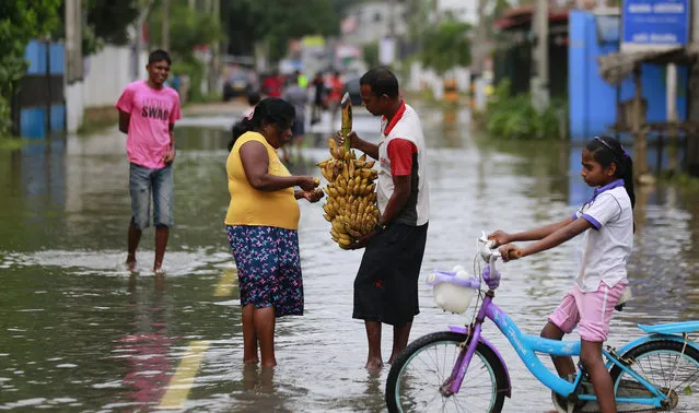 A Sri Lankan man offers bananas to a women in a flooded street in Colombo, Sri Lanka, Sunday, May 28, 2017. (Photo by Eranga Jayawardena/AP Photo)