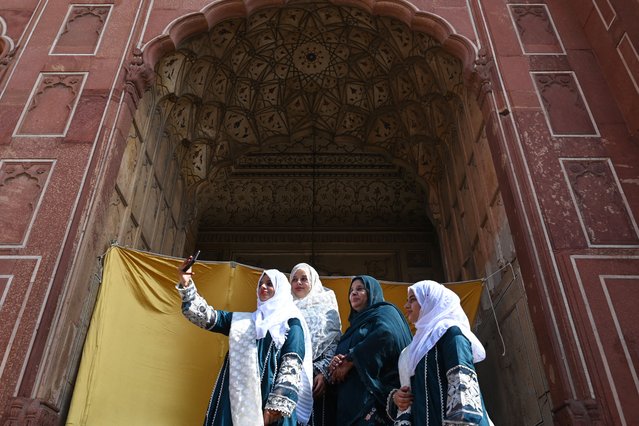 Women takes a selfie after offering prayers at the Badshahi mosque during the Eid al-Adha or the 'Festival of Sacrifice, in Lahore on June 17, 2024. (Photo by Arif Ali/AFP Photo)