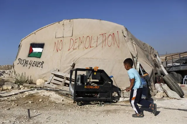 In this Tuesday, July 21, 2015, photo, a Palestinian boy runs outside his family tent in the village of Susiya, south of the West Bank city of Hebron. (Photo by Majdi Mohammed/AP Photo)