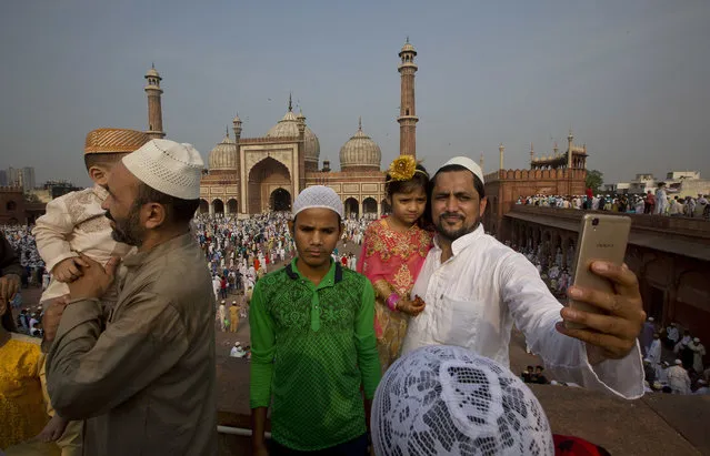 An Indian Muslim takes a selfie as their children in new dresses join festivities after offering Eid al-Fitr prayers at the Jama Masjid mosque in New Delhi, India, Monday, June 26, 2017. Eid al-Fitr marks the end of the Muslims' holy fasting month of Ramadan. (Photo by Manish Swarup/AP Photo)