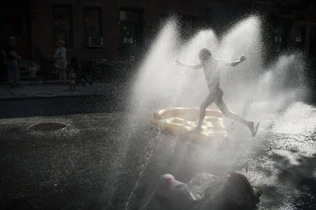 A child cools off in the spray of water from a fire hydrant during a block party in the Brooklyn borough of New York on Saturday, May 21, 2022, where New Yorkers experienced summer-like weather and temperatures are expected to peak at nearly 90 degrees (Fahrenheit) over the weekend, roughly ten degrees hotter than average for New York City in late May, according to meteorologists. (Photo by Wong Maye-E/AP Photo)