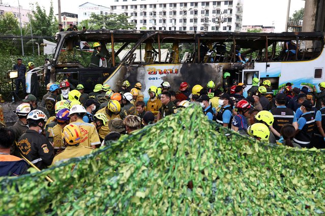 A green cover is set up as firefighters remove bodies from a burnt-out bus that was carrying teachers and students from Wat Khao Phraya school, reportedly resulting in fatalities and injuries, on the outskirts of Bangkok, Thailand, on October 1, 2024. (Photo by Chalinee Thirasupa/Reuters)