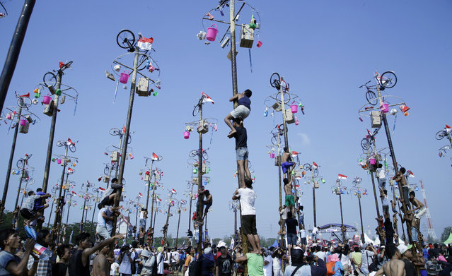 Indonesian men climb greased poles to retrieve prizes such as bicycles and rice cookers as part of the Independence Day festivities at Ancol Beach in Jakarta, Indonesia, Monday, August 17, 2015. Indonesia marked the 70th anniversary of its declaration of independence from Dutch colonial rule on Monday. (Photo by Tatan Syuflana/AP Photo)