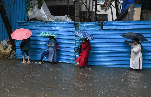 Women holding umbrellas are crossing a flooded street amidst heavy rain in Mumbai on July 5, 2022. Mumbai experienced flooded streets in low-lying areas, and traffic was slow-moving across the city due to heavy rain. Indian Meteorological Department (IMD) has predicted moderate to heavy rain in the next 24 hours in the city. (Photo by Avishek Das/SOPA Images/LightRocket via Getty Images)