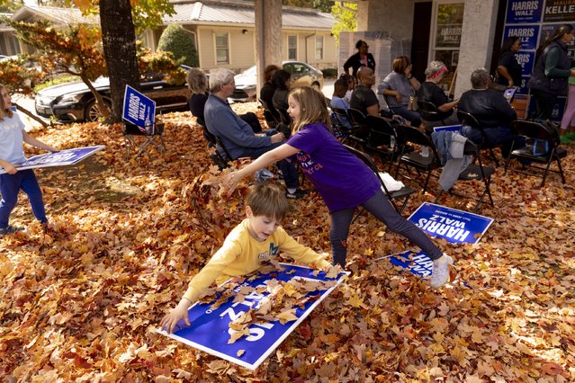 Laine Hollberg (right), 7, throws a pile of leaves while siblings Clover (left), 7, and Cliff Kambic (center), 4, play at the Fayette County Canvass Launch where Senator Ralph Warnock later spoke to a crowd in Fayetteville, Georgia on election day November 5, 2024. (Photo by Kendrick Brinson for The Washington Post)