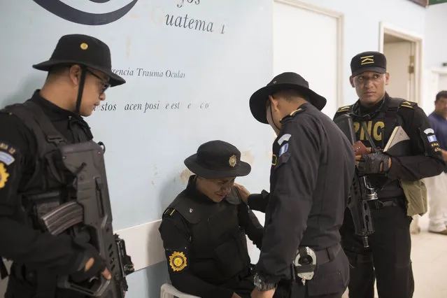 National Civil Police officer Walter Valdez is comforted by his colleagues after learning that his brother was of the two prison guards killed in an attack at the Roosevelt Hospital, in Guatemala City, Wednesday, August 16, 2017. (Photo by Luis Soto/AP Photo)