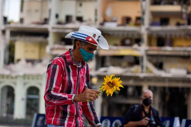 A man brings a sunflower to a vigil for the victims of the Saratoga Hotel accident in Havana, on May 13, 2022. The death toll from last week's hotel explosion in Cuba has risen to 46 after a man who was in critical condition in hospital died, the public ministry said on Friday. (Photo by Yamil Lage/AFP Photo)