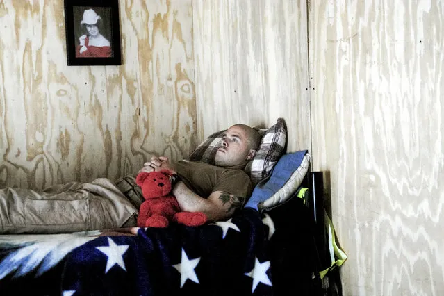 While most photos of war are of fighting, the majority of time is spent waiting around. This helicopter medic waits for a call from a radio channel dedicated to casualty reports. His girlfriend gave him the teddy bear. Here: A flight medic rests and watches TV while waiting for a mission in the medevac section of FOB Falcon. (Photo and caption by Van Agtmael/Harrison Jacobs/Magnum Photos)
