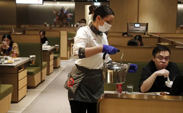 In this March 5, 2020, photo, a waitress of the Chinese restaurant Hot Pot serves customers in London. While white collar workers trying to avoid contagion can work from home or call in sick if they experience symptoms of the virus, such precautions are not an options for the millions of waiters, delivery workers, cashiers, ride-hailing drivers, museum attendants and countless others who routinely come into contact with the public. (Photo by Frank Augstein/AP Photo)