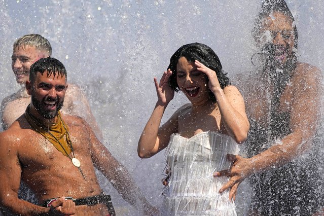 Members of the Australian cabaret & circus troupe Briefs cool down in a fountain on the Southbank in London, Tuesday, July 19, 2022. Britain shattered its record for highest temperature ever registered Tuesday, with a provisional reading of 39.1 degrees Celsius (102.4 degrees Fahrenheit), according to the country's weather office – and the heat was only expected to rise. (Photo by Frank Augstein/AP Photo)