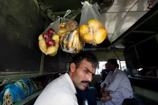 A man sits in a train, under the suspended bags of fruits, as he leave for his hometown ahead of the Eid al-Fitr festival, at the Cantonment railway station in Karachi, Pakistan, July 5, 2016. (Photo by Akhtar Soomro/Reuters)