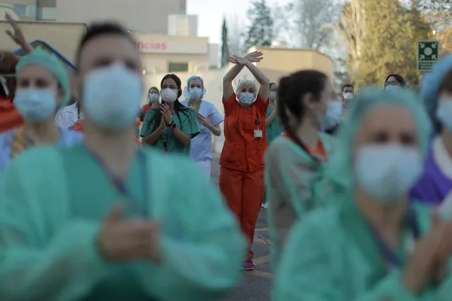 Health workers applaud as people react from their houses in support of the medical staff that are working on the COVID-19 virus outbreak at the Gregorio Maranon hospital in Madrid, Spain, Wednesday, April 1, 2020. (Photo by Manu Fernandez/AP Photo)