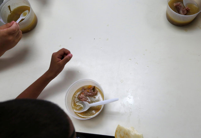 A kindergarten student is seen next to a bowl of soup cooked for him and his classmates during an activity for the end of the school year at the Padre Jose Maria Velaz school in Caracas, Venezuela July 12, 2016. (Photo by Carlos Jasso/Reuters)