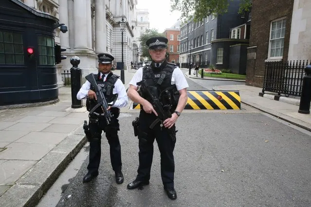 Armed police officers pose for the media in Downing Street, central London August 29, 2014. Britain's Prime Minister David Cameron said on Friday he planned to introduce new legislation to make it harder for Britons to travel to Syria and Iraq to fight alongside Islamist extremists. Cameron, who said he would detail his plans in parliament on Monday to confiscate passports, was speaking as Britain raised its international terrorism threat level to “severe”, its second highest level. (Photo by Paul Hackett/Reuters)