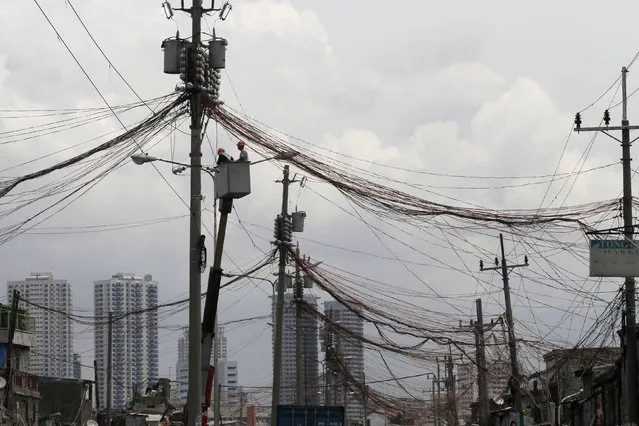 Workers standing in a hydraulic lift examine illegal electrical connections during a routine check on utility poles along a road in a slum area in Manila September 8, 2014. (Photo by Romeo Ranoco/Reuters)