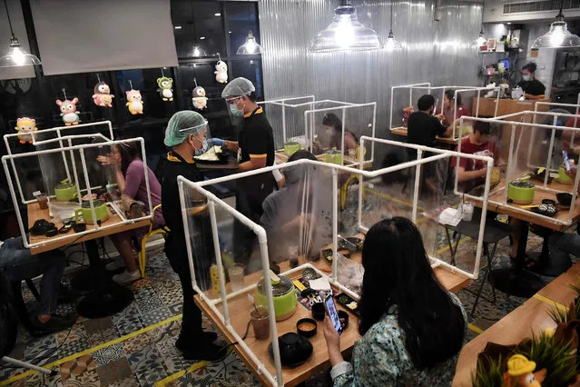People eat in between plastic partitions, set up in an effort to contain any spread of the COVID-19 coronavirus, at the Penguin Eat Shabu hotpot restaurant in Bangkok on May 5, 2020. (Photo by Lillian Suwanrumpha/AFP Photo)