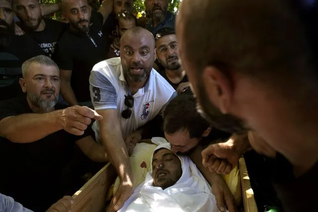 A mourner kisses the head of Palestinian Abdul-Al Omar Abdul-Al, 24, who was on a boat carrying migrants from Lebanon that sank in Syrian waters, during his funeral in the Palestinian refugee camp of Nahr el-Bared near the northern city of Tripoli, Lebanon, Saturday, September 24, 2022. (Photo by Bilal Hussein/AP Photo)