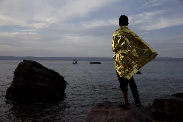A refugee wrapped in a thermal blanket  looks at a dinghy full of migrants and refugees approach the coast of Lesbos island, Greece, Wednesday, September 9, 2015. The head of the European Union's executive says 22 of the member states should be forced to accept another 120,000 people in need of international protection who have come toward the continent at high risk through Greece, Italy and Hungary. (Photo by Petros Giannakouris/AP Photo)