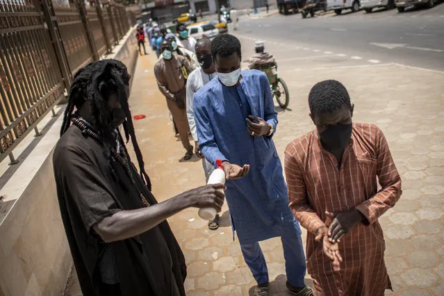 In this photo taken Friday, May 15, 2020, followers of the Senegalese Mouride brotherhood, an order of Sufi Islam, sanitize their hands as they arrive to attend Muslim Friday prayers at West Africa's largest mosque the Massalikul Jinaan, in Dakar, Senegal. A growing number of mosques are reopening across West Africa even as confirmed coronavirus cases soar, as governments find it increasingly difficult to keep them closed during the holy month of Ramadan. (Photo by Sylvain Cherkaoui/AP Photo)