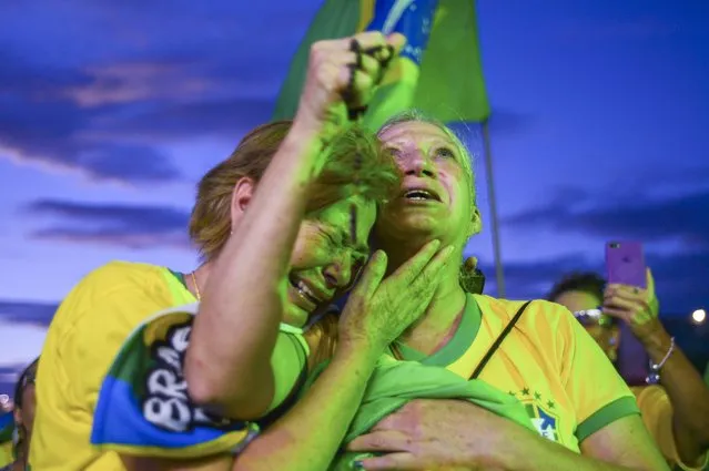 Supporters of Brazilian President Jair Bolsonaro embrace as they listen to partial results after polls closed in a presidential run-off election in Brasilia, Brazil, Sunday, October 30, 2022. On Sunday, Brazilians had to choose between incumbent Bolsonaro and his rival, former President Luiz Inacio Lula da Silva, after neither got enough support to win outright in the Oct. 2 general election. (Photo by Ton Molina/AP Photo)