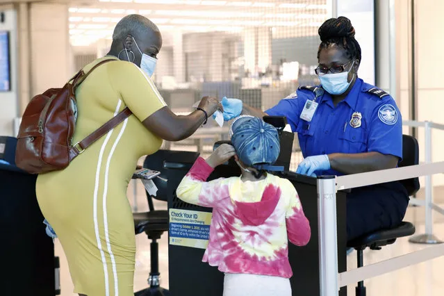 TSA agent Patrisa Johnson assist travelers as they clear security for flights out of Love Field in Dallas, Wednesday, June 24, 2020. (Photo by Tony Gutierrez/AP Photo)