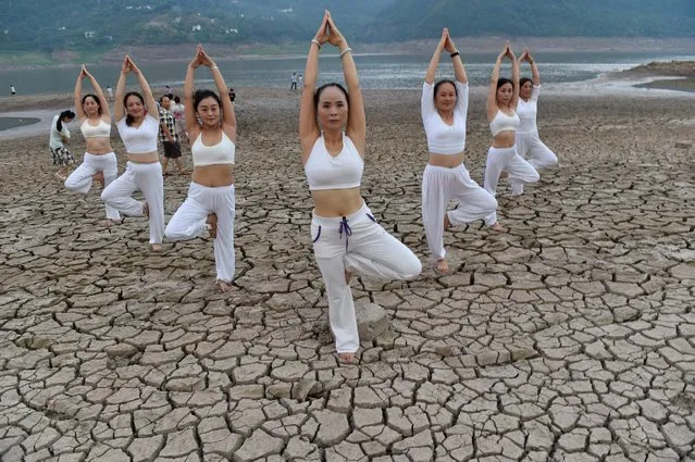Women perform yoga on a dried river bank in Yunyang county, Chongqing Municipality, August 21, 2016. (Photo by Reuters/China Daily)