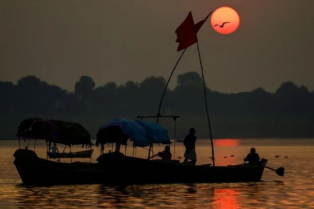 Boatmen are silhouetted against the setting sun at Sangam, the confluence of the rivers Ganges, Yamuna, and mythical Saraswati, in Prayagraj on November 16, 2022. (Photo by Sanjay Kanojia/AFP Photo)