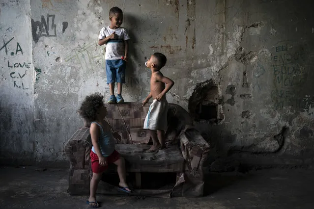 In this September 11, 2017 photo, children play inside a squatter building that used to house the Brazilian Institute of Geography and Statistics (IBGE) in the Mangueira slum of Rio de Janeiro, Brazil. Budgetary pressures and the conservative policies of President Michel Temer are translating into cuts in social services, including the “Bolsa Familia” program that gives monthly small subsidies to qualifying low-income people. (Photo by Felipe Dana/AP Photo)