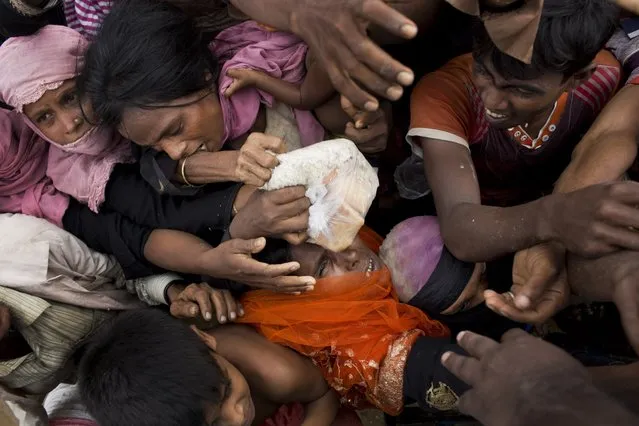 Rohingya Muslims, newly arrived from Myanmar, scuffle for puffed rice food rations donated by local volunteers in Kutupalong, Bangladesh, on September 9, 2017. (Photo by Bernat Armangue/AP Photo)