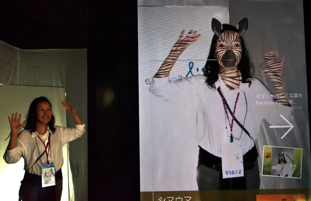 Japan's IT company Mediaturge employee demonstrates an animal morphing technology “Animal Selfie” at the annual Digital Contens Expo in Tokyo on October 23, 2014. The user can wear animal skin such as giraffe, leoppard and zebra with a technology augmented reality. (Photo by Yoshikazu Tsuno/AFP Photo)