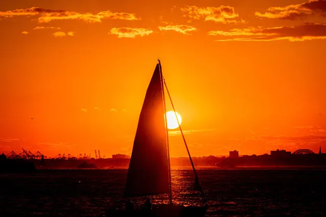A sailboat passes by Brooklyn Bridge Park during sunset, Monday, September 26, 2022. (Photo by Julia Nikhinson/AP Photo)