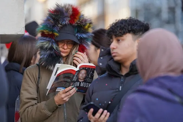 A person reads a book about Twitter, Inc. owner Elon Musk, as they queue outside Selfridges, ahead of the store opening for the traditional Boxing Day sales in London, Britain on December 26, 2022. (Photo by Maja Smiejkowska/Reuters)